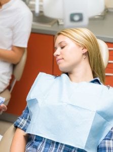 Woman asleep in dental chair from sedation dentistry